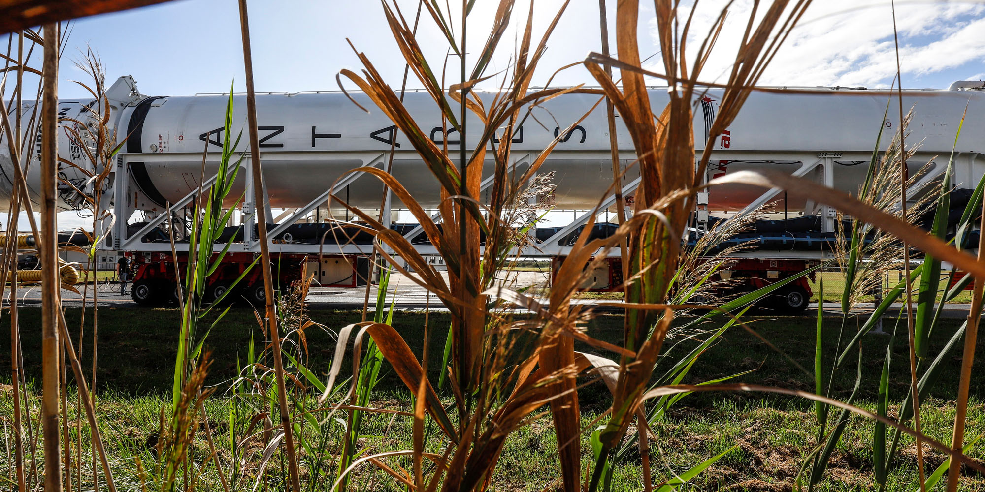 AntaresRocket_Wallops Green plants only allow a peek of the Antares Rocket as it is transported to the launchpad in Wallops Island, Virginia