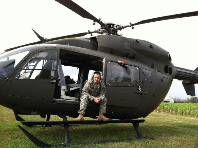 Man in military uniform sitting in open door of helicopter on ground_Rob military transition Man in military uniform sitting in open door of helicopter on ground